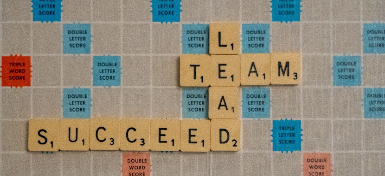 Scrabble board with the words Lead, Team and Succeed