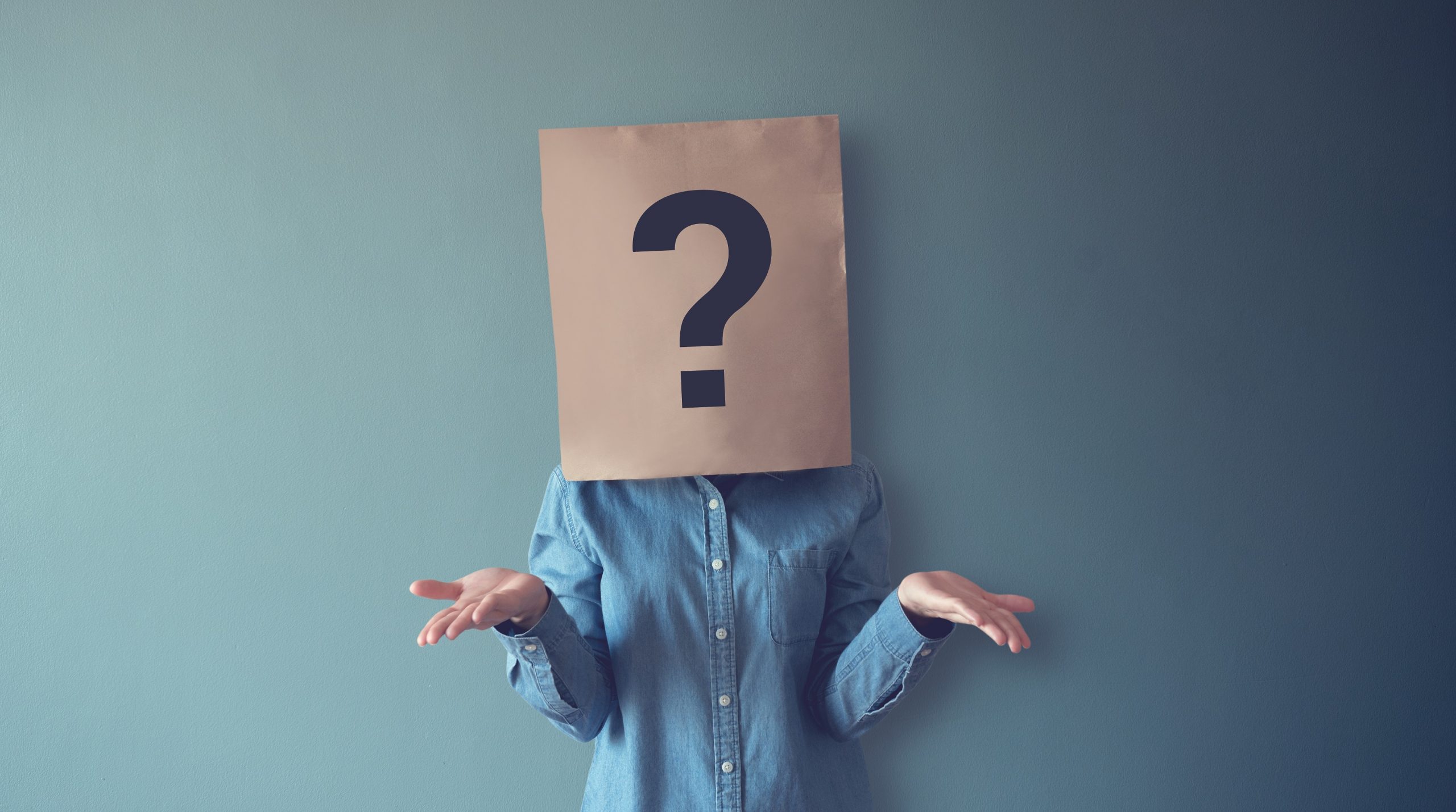 Woman confused with a paper bag featuring a question mark on her head
