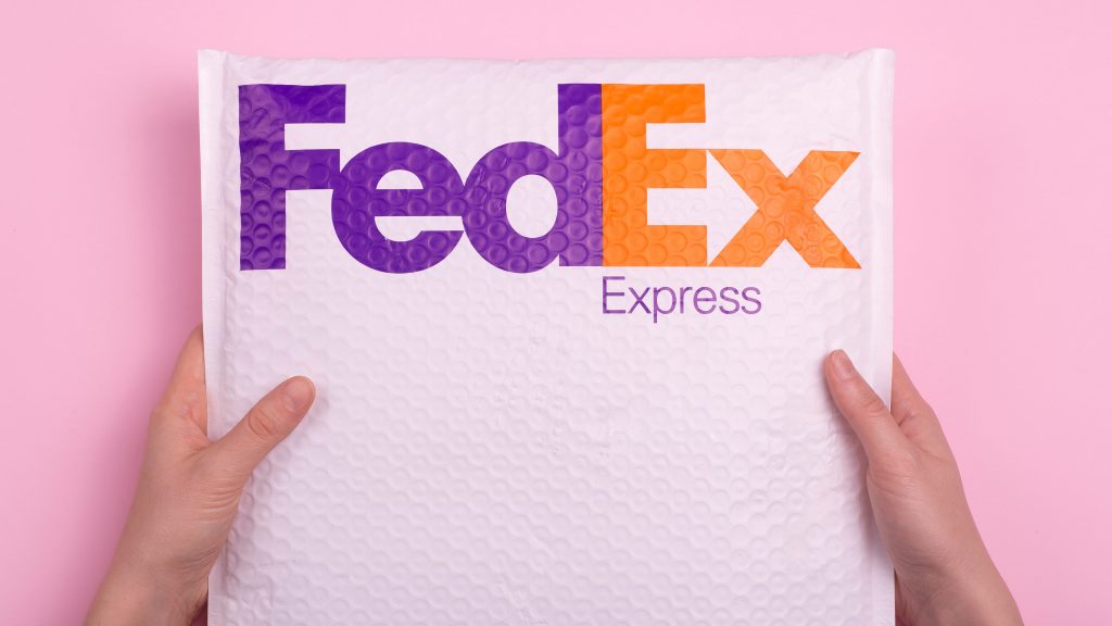 Hands delivering a FedEx package