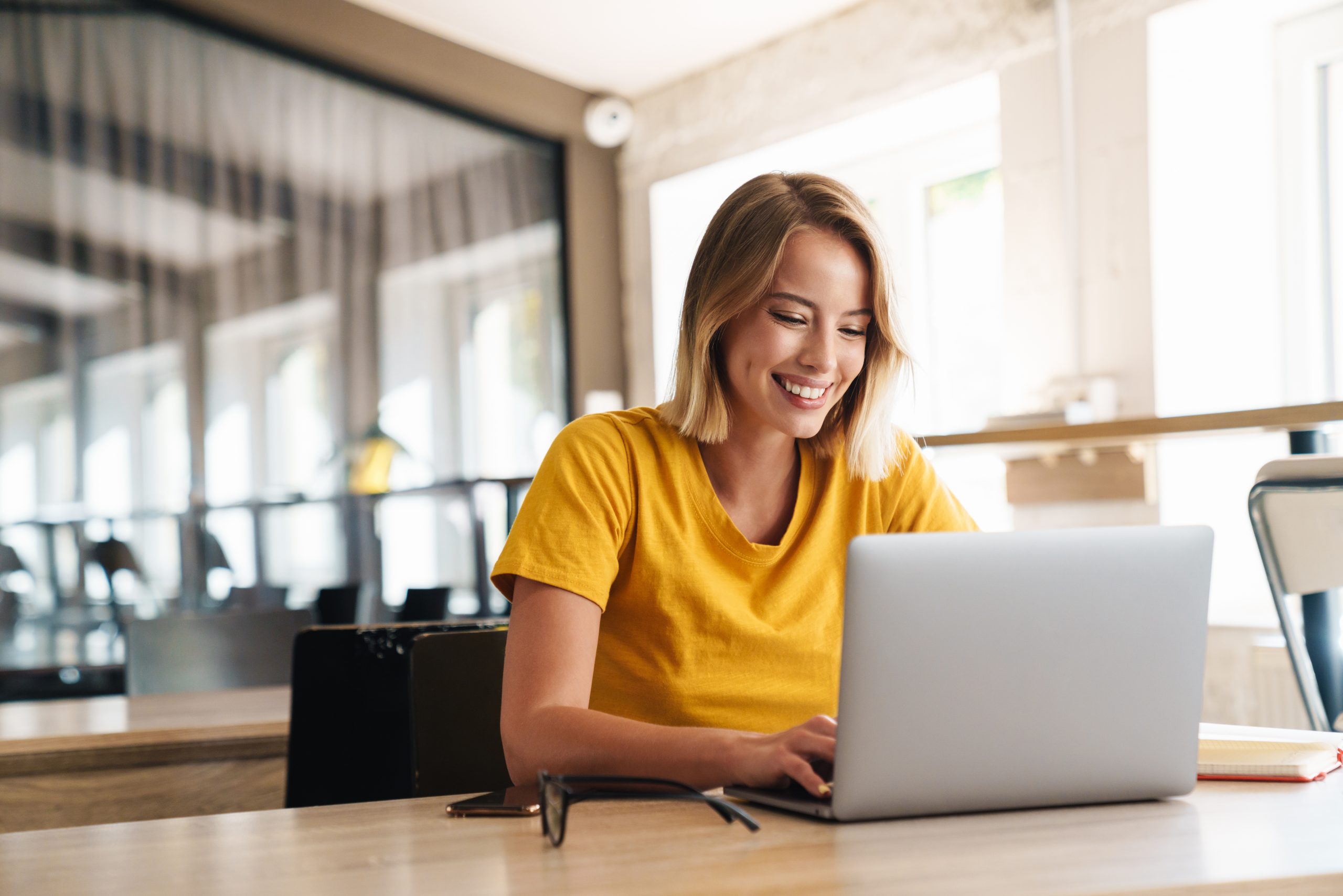 Photo of joyful nice woman using laptop and smiling while sitting and using a laptop