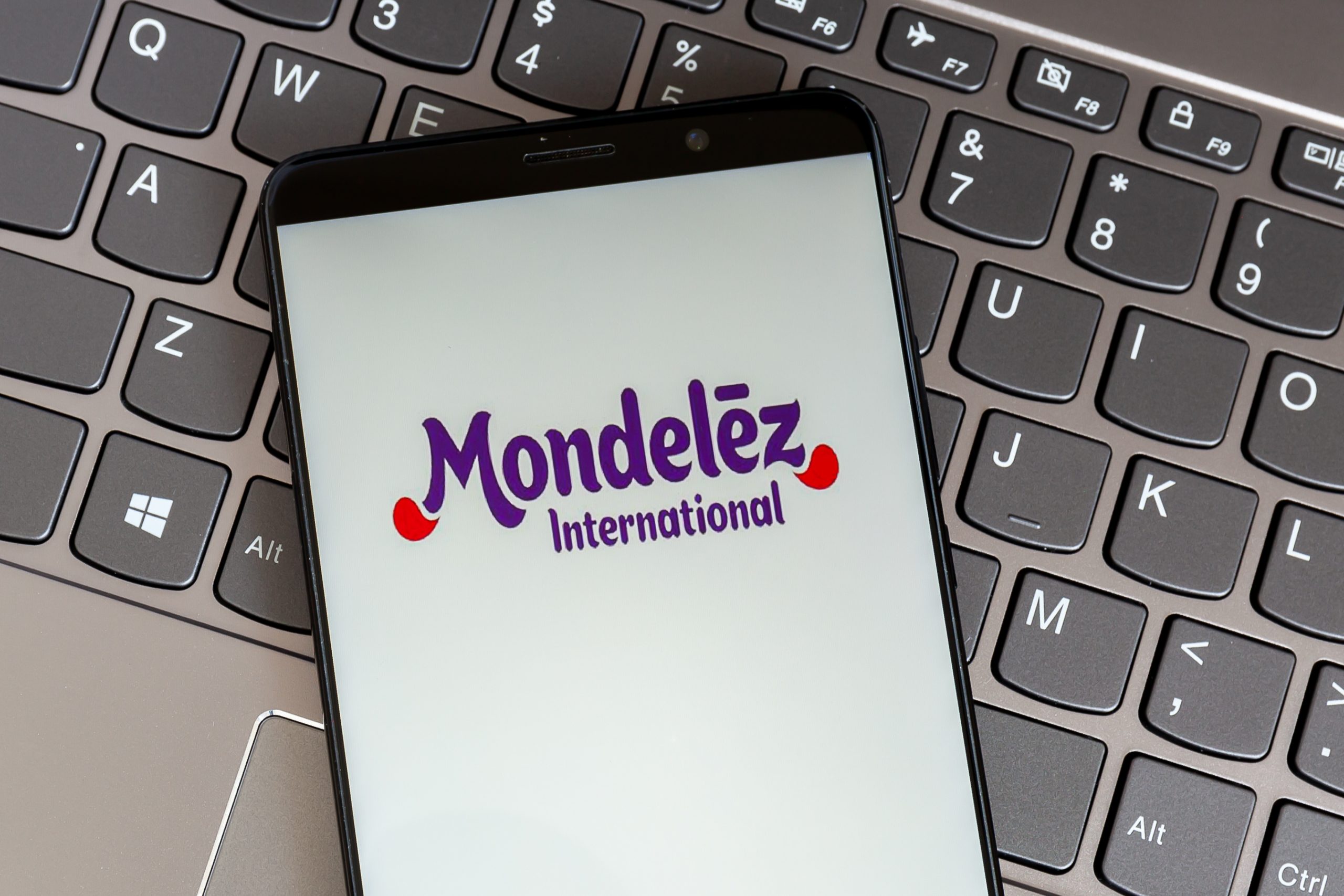 Mondelez logo displayed on a cellphone screen that sits on top of a computer keyboard