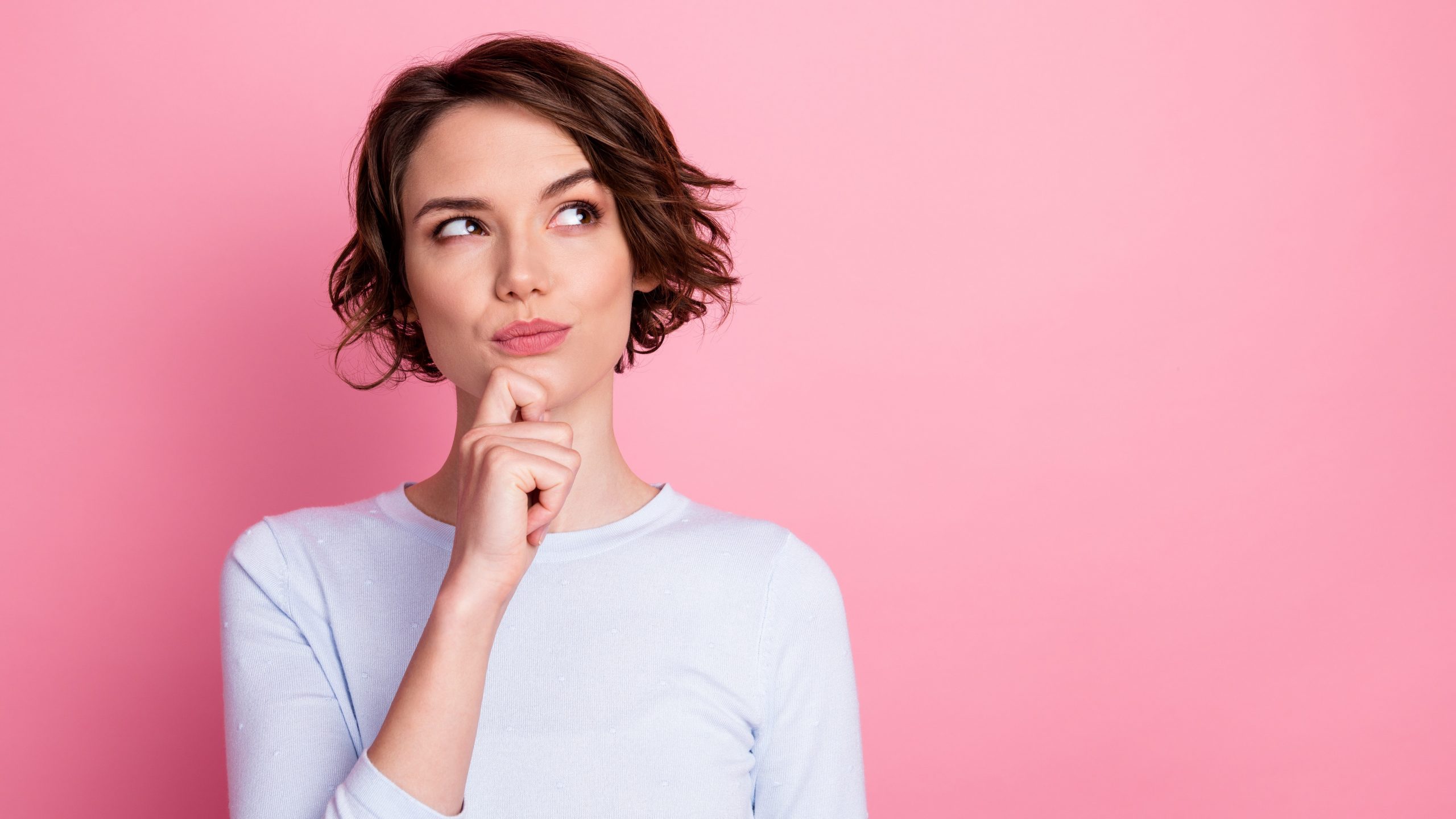 Woman wonders in front of a pink background