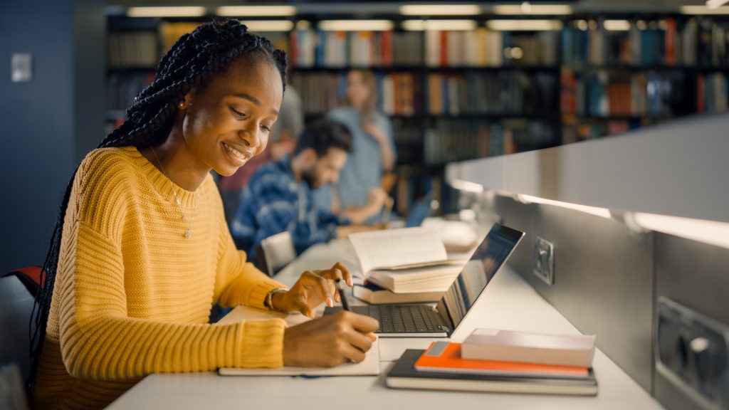 Woman smiles as she studies with her laptop