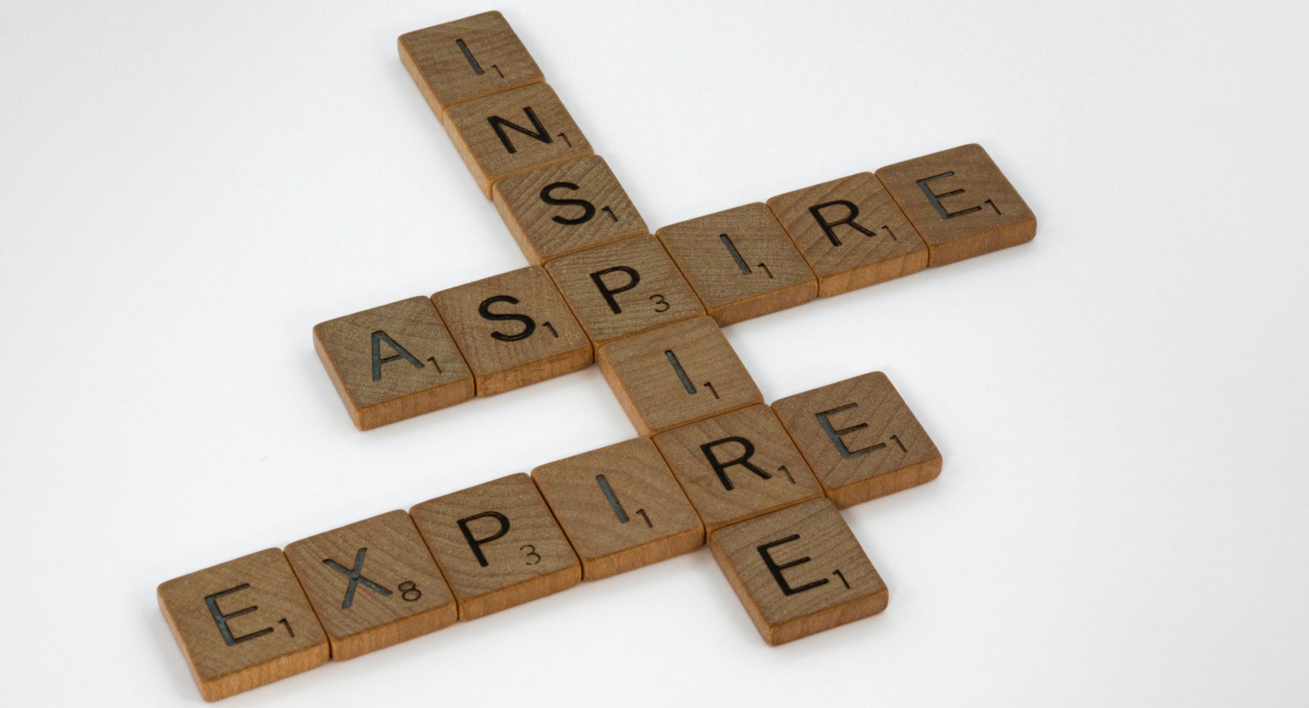 Wood pieces spell the words 'Inspire', 'Aspire', and 'Expire'