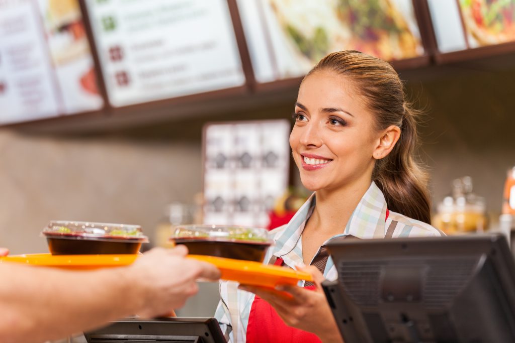 Restaurant worker serving two fast food meals with smile. woman
